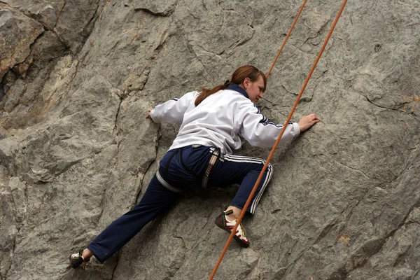 Young man climbing vertical wall with valley view on the background — Stock Photo, Image