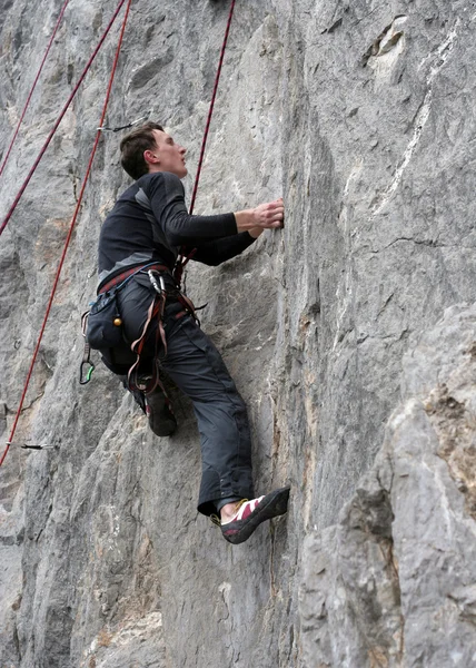 Young man climbing vertical wall with valley view on the background — Stock Photo, Image