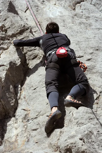 Young man climbing vertical wall with valley view on the background — Stock Photo, Image