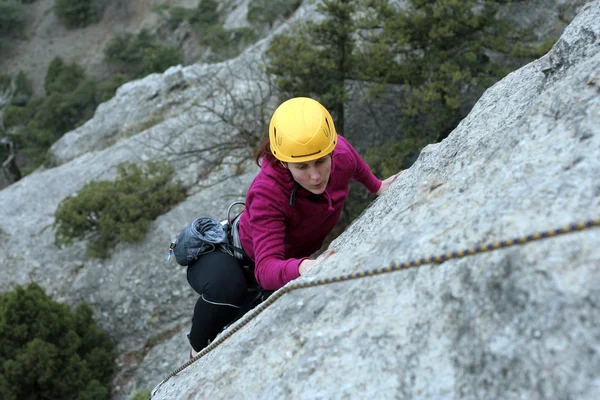 Young man climbing vertical wall with valley view on the background — Stock Photo, Image