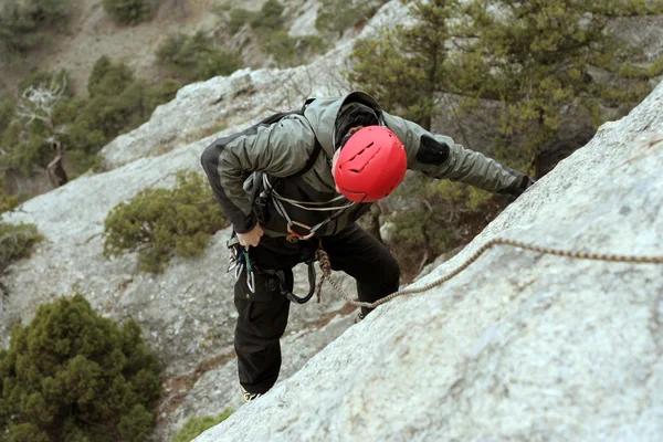 Jeune homme escalade mur vertical avec vue sur la vallée sur le fond — Photo