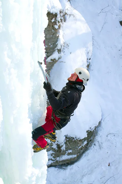 Man climbing frozen waterfall Stock Photo