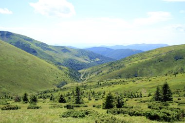 Dağlardaki yaz manzarası ve bulutlu koyu mavi gökyüzü.