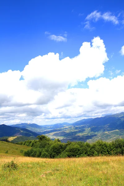 Letní krajina se zelenou trávou, silnicí a mraky — Stock fotografie