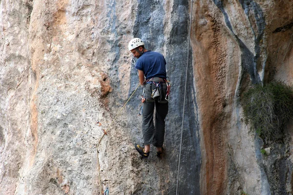 Rock climber climbing up a cliff — Stock Photo, Image