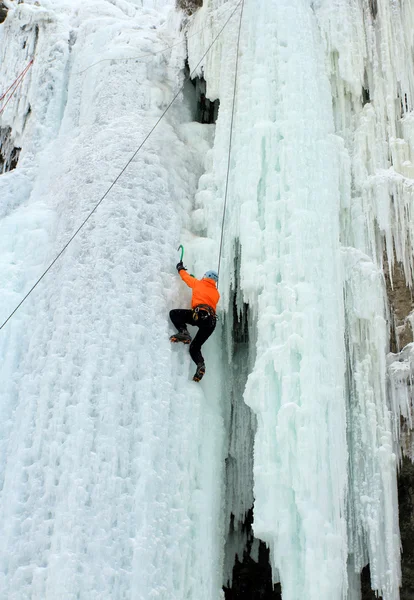 Escalador de gelo luta até uma cachoeira congelada . — Fotografia de Stock