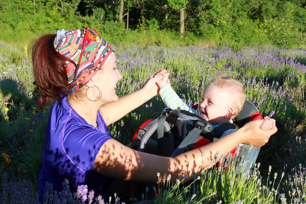 Мама идет с ребенком в ребенке, неся его
.