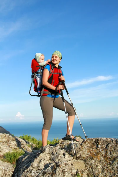 Mãe com carrinho de bebê carregando um filho em alpes em um dia ensolarado — Fotografia de Stock