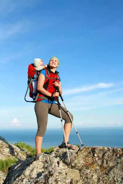 Mother with baby carrier carrying a son in alps on a sunny day — Stock Photo, Image