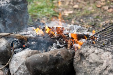 Büyük taşlarla çevrili yanmış bir kütüğün üzerinde dans dilleriyle şenlik ateşi.