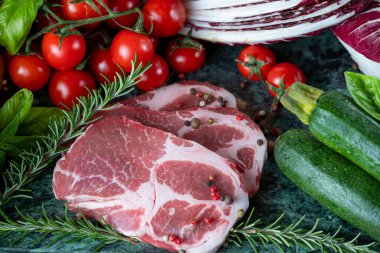 Koyu yeşil mermer tahtada taze et, baharat ve çeşitli sebzeler.