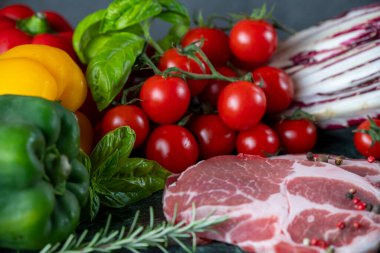 Koyu yeşil mermer tahtada taze et, baharat ve çeşitli sebzeler.