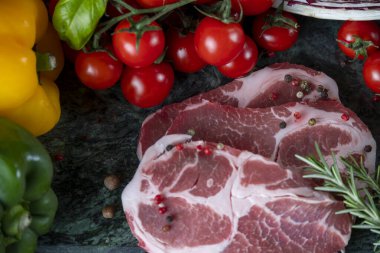 Koyu yeşil mermer tahtada taze et, baharat ve çeşitli sebzeler.