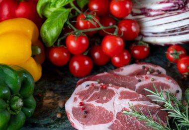 Koyu yeşil mermer tahtada taze et, baharat ve çeşitli sebzeler.