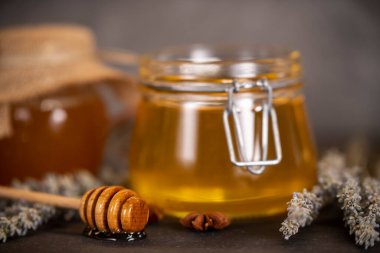 Kavanozlarda çiçek balı ve arka planda bal için ahşap kaşık.