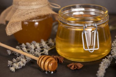 Kavanozlarda çiçek balı ve arka planda bal için ahşap kaşık.