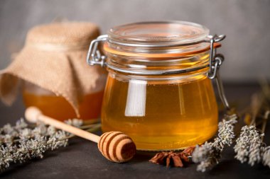 Kavanozlarda çiçek balı ve arka planda bal için ahşap kaşık.