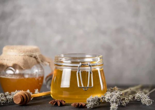 Kavanozlarda çiçek balı ve arka planda bal için ahşap kaşık.