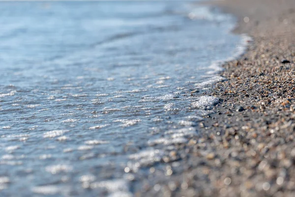 砂浜には透明度の高い海水を背景に小さな貝殻が点在し — ストック写真