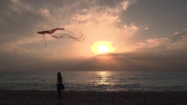 Kid hrát na pláži na pobřeží, dítě létání draka při západu slunce na oceánu, Malá holka na pobřeží v letní dovolené — Stock video