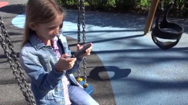 Child Playing Smartphone in Swing, Kid Browsing Internet on Tablet in Park, Girl Writing Messages on Phone at Playground