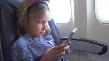 Child Playing Tablet in Plane, Small Girl Portrait Using Smartphones Airplane, People Airline Transportation