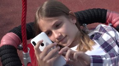 Child Playing Smartphone in Swing, Teenager Kid Browsing Internet on Smart Phone in Park, Adolescent Girl Outdoor at Playground