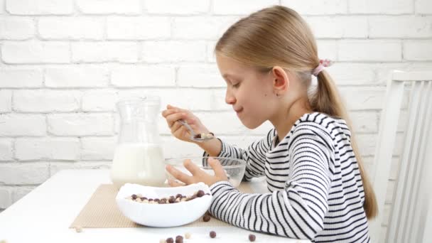 朝食にミルクとシリアルを食べる子供,キッチンの子供,ブロンドの10代の女の子は食事で健康的な食べ物を味わう,子供の栄養 — ストック動画