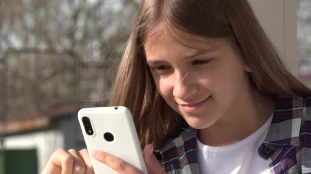 Adolescente niño jugando Smartphone, Kid navegar por Internet en el teléfono inteligente en el parque, Adolescente niña utilizar dispositivos al aire libre en el patio de recreo — Vídeos de Stock