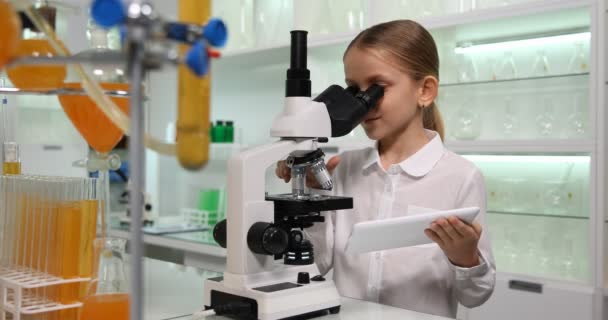 Dzieciak korzystający z mikroskopu w laboratorium chemicznym, dziecko z tabletem uczące się w laboratorium szkolnym, uczące się eksperymentów w klasie naukowej — Wideo stockowe