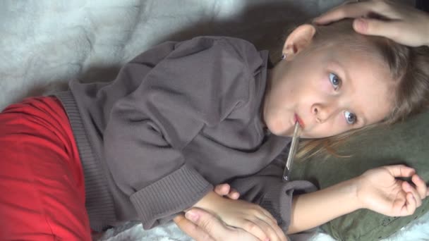 体温計で病気の子供 ベッドで病気の悲しい子供 コロナウイルスの母親のペッティングガール額 ファミリーメディカルヘルスケア — ストック動画