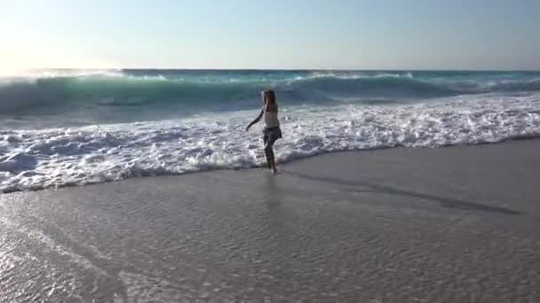 Flicka leker på stranden, Kid kör på stranden vid solnedgången, lilla barn tittar på havsvågor på kustlinjen Shore i sommar semester — Stockvideo
