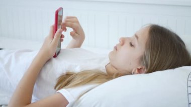 Çocuk Yatakta Akıllı Telefon Oynuyor, Genç Çocuk İnternet Tarıyor, Çevrimiçi Akıllı Telefon Cihazı Alışverişi, Kız Evde Alet Kullanıyor