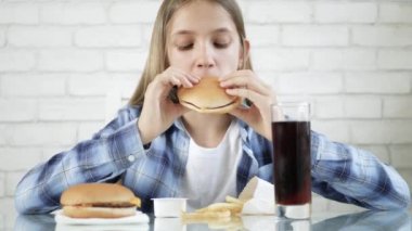 Fast food yiyen çocuk, restoranda hamburger yiyen çocuk, çizburgerli sarışın kız, meyve suyu içen çocuk.