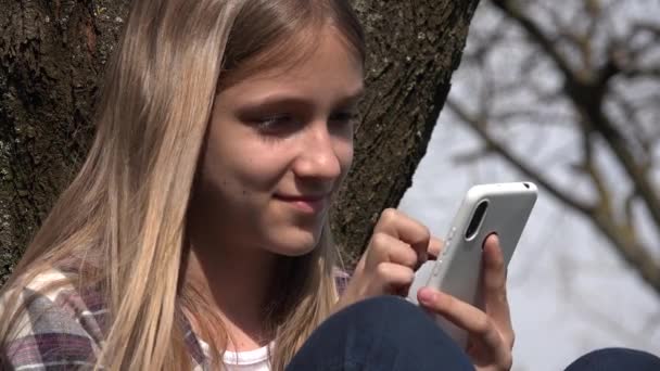 Flicka Spela Smartphone Tree Tonåring Kid Bläddra Internet Smart Phone — Stockvideo