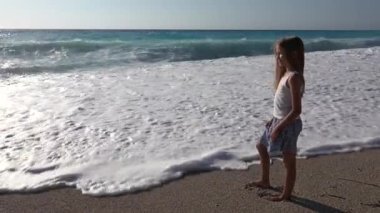 Girl Playing on Sea Beach in Sunset, Kid Watching Ocean Waves on Coastline, Blonde Child Portrait on Shore in Summer Vacation