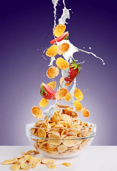 Vallende gouden cornflakes en aardbei met splash van melk — Stockfoto