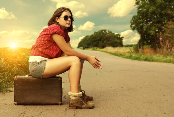 Auto stop traveller sitting on suitcase at the road — Stock Photo, Image