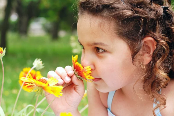 Malá holka vonící květ — Stock fotografie
