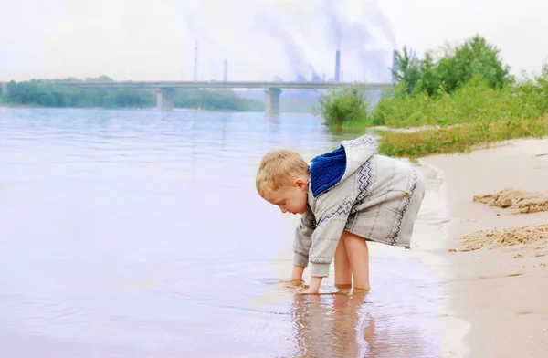 Little boy on the river coast near industrial plant — Stock Photo, Image