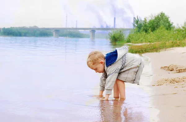 Ragazzino sulla costa del fiume vicino stabilimento industriale — Foto Stock