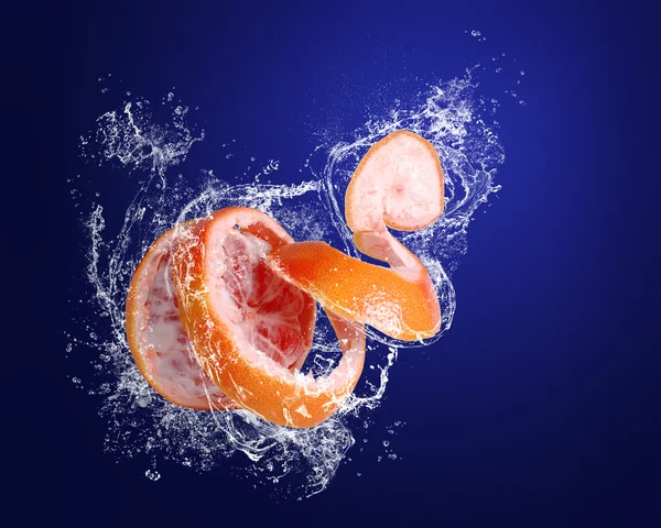 Red grapefruit with skin peeled like a spiral in water splashes — Stock Photo, Image