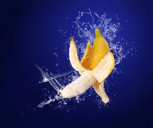 Yellow banana in water splashes on the dark blue background