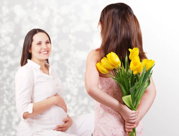 Filha pequena tem uma flores para sua mãe grávida — Fotografia de Stock