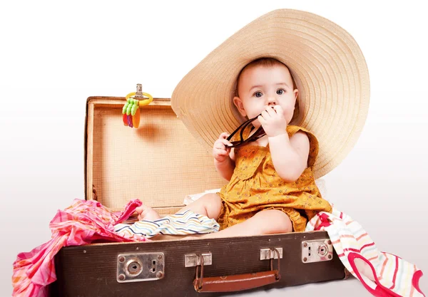 Graciosa niña sentada en una vieja maleta — Foto de Stock