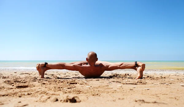 Hombre musculoso haciendo yoga en la playa — Foto de Stock