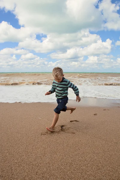 Glad liten pojke som körs vid kusten — Stockfoto