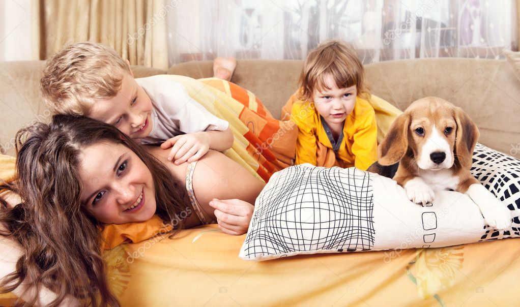 Happy children plaing with puppy in bed