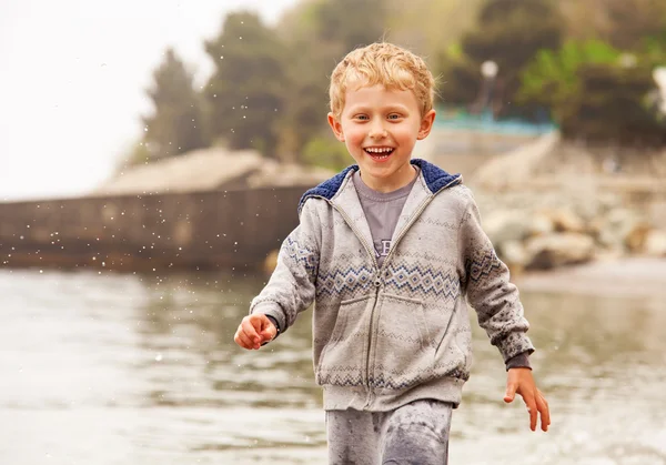 Schattige lachende kleine jongen uitvoeren in waterdruppels — Stockfoto