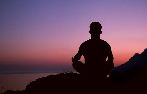 Sitter man silhuetten i meditation pose — Stockfoto